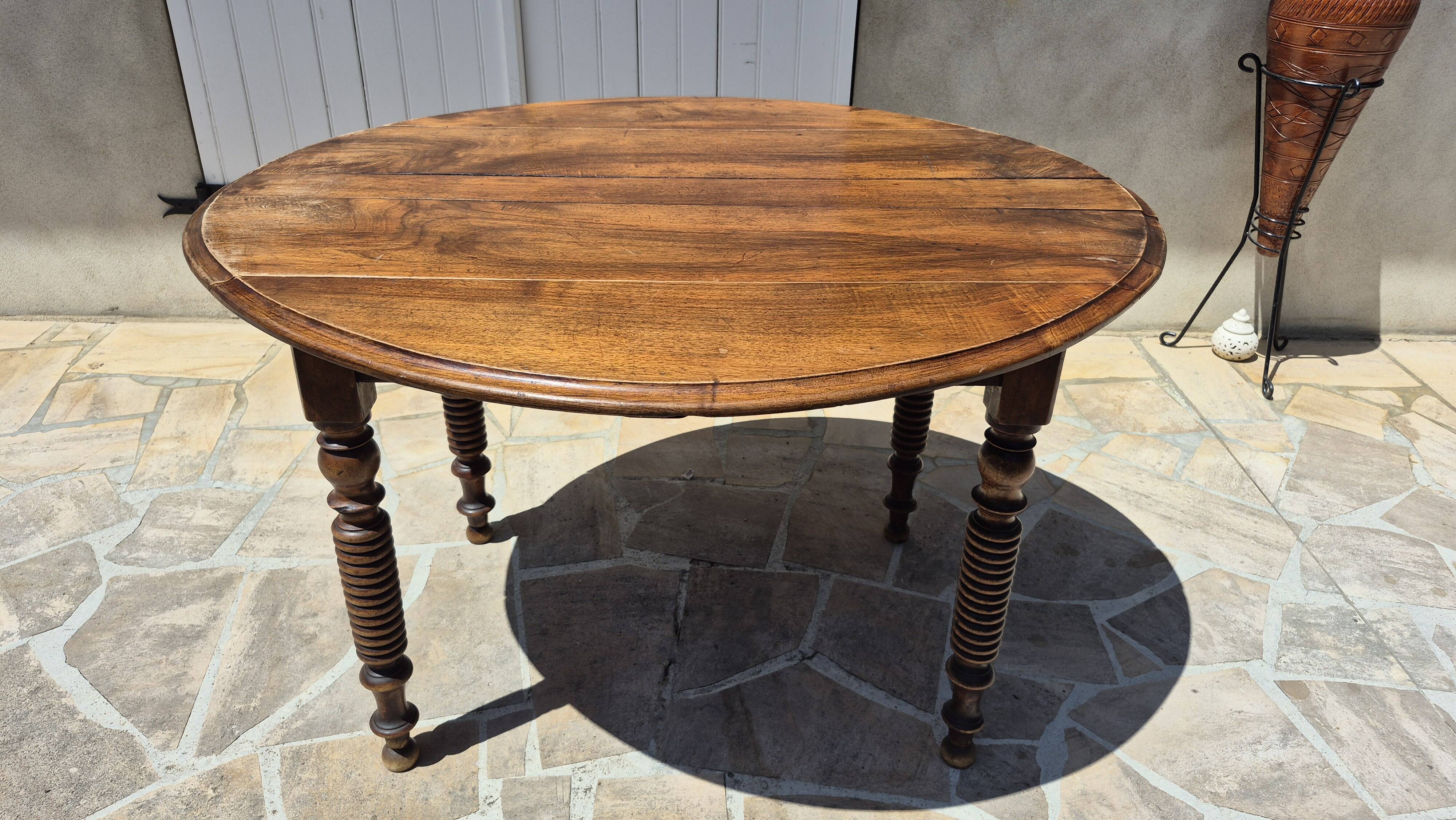 Round dining table with a drop-leaf top in solid walnut, late 19th century.