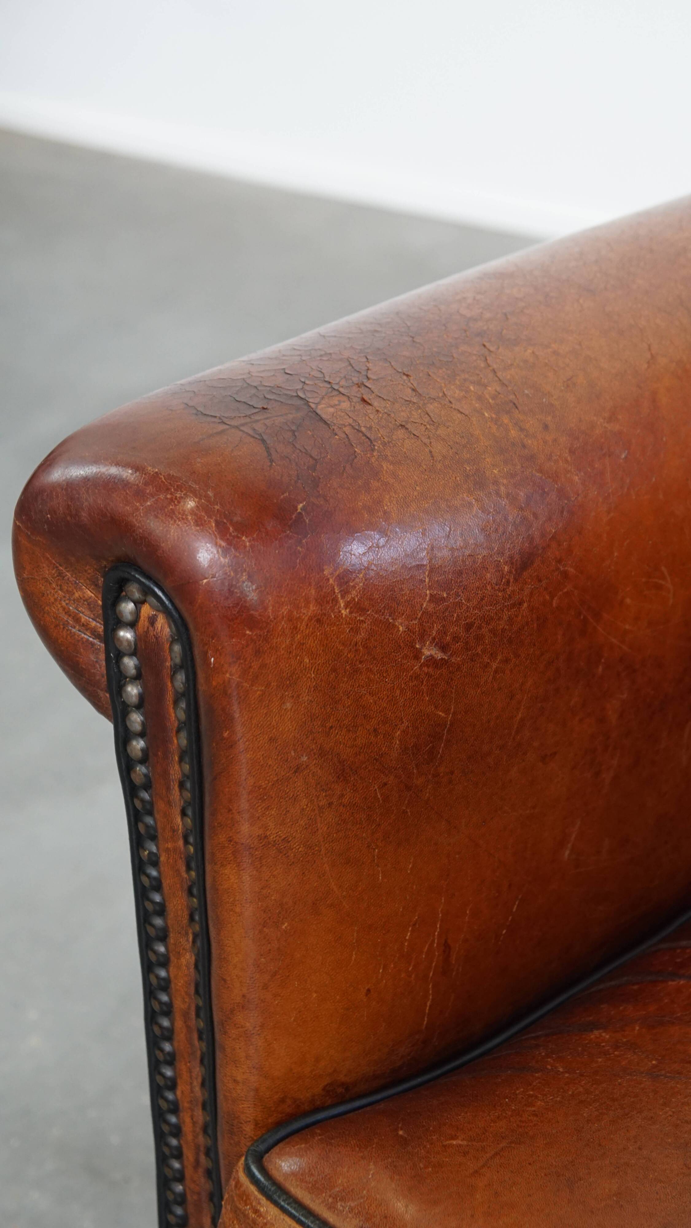 Sheepskin leather armchair in a cognac color with black piping