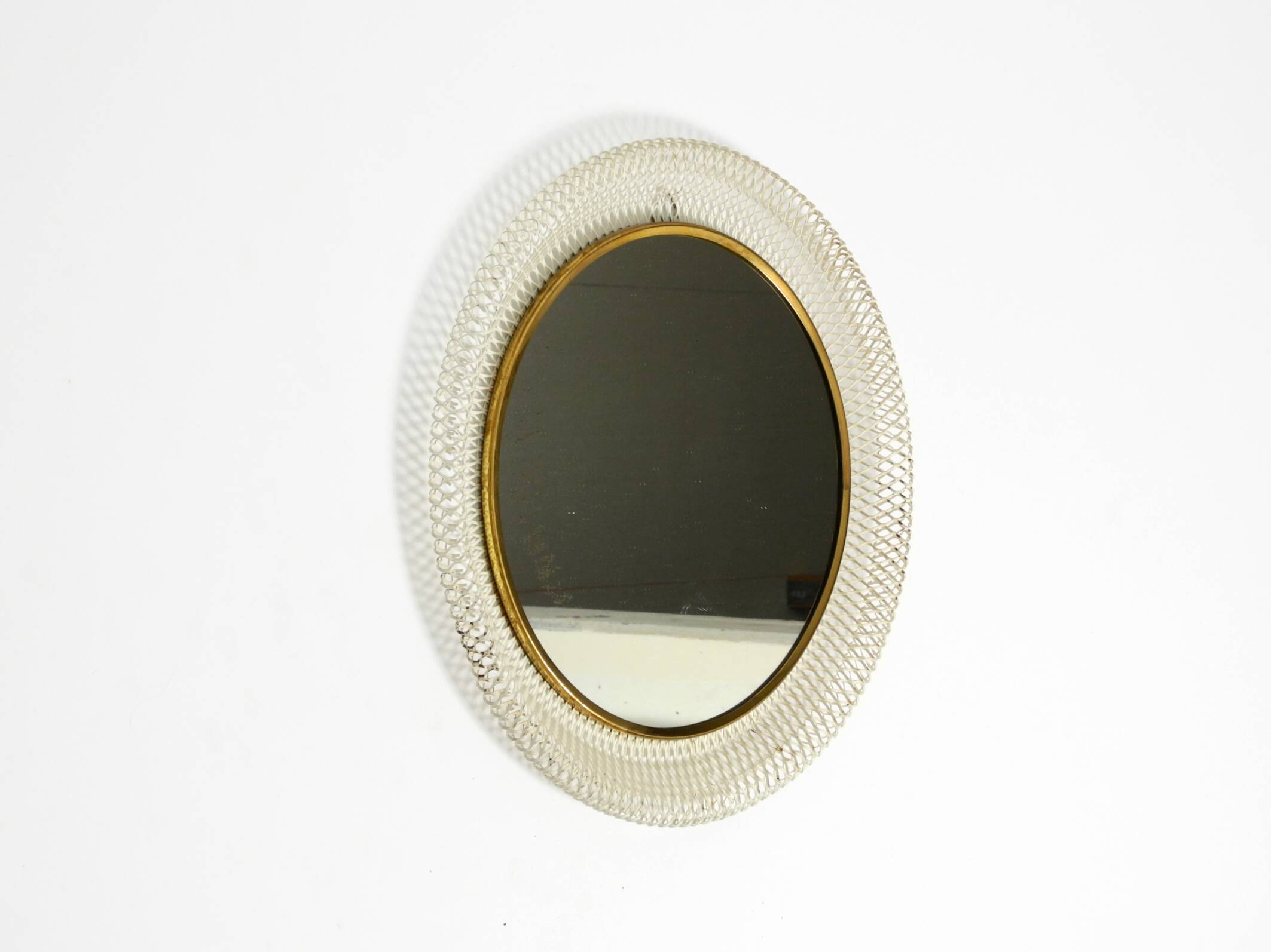 Mid Century Modern round wall mirror with a white expanded metal frame
