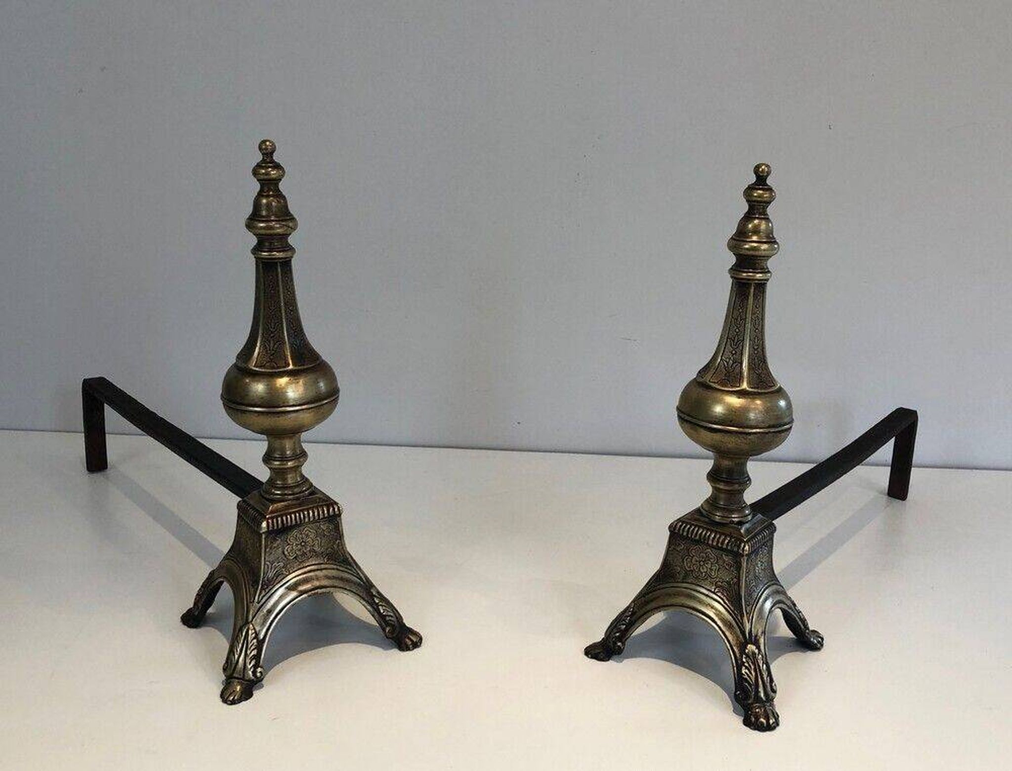 Pair of chiselled bronze and wrought iron fire dogs in the Louis XVI style.