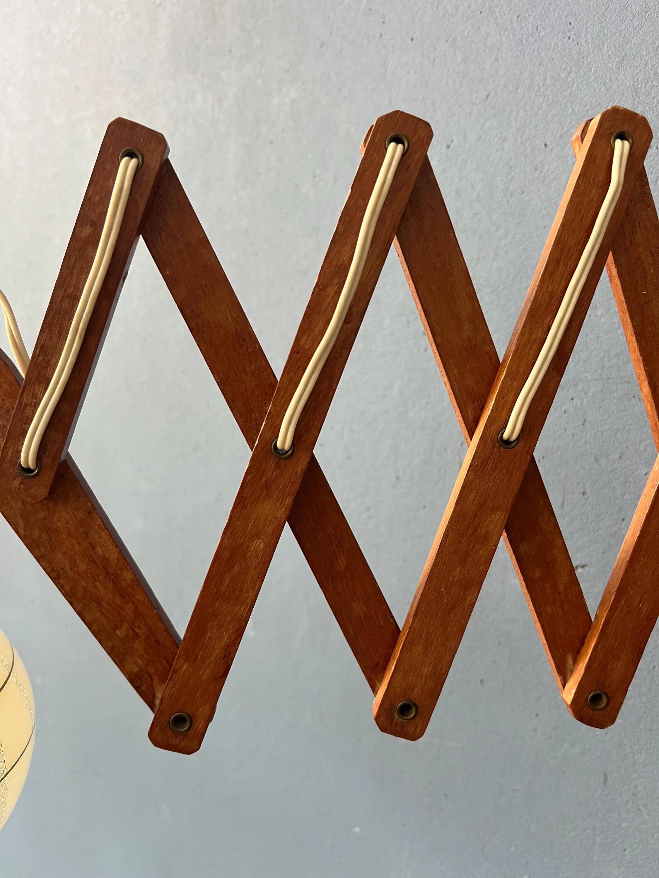 Vintage wall lamp with teak wood scissors and glass shade.