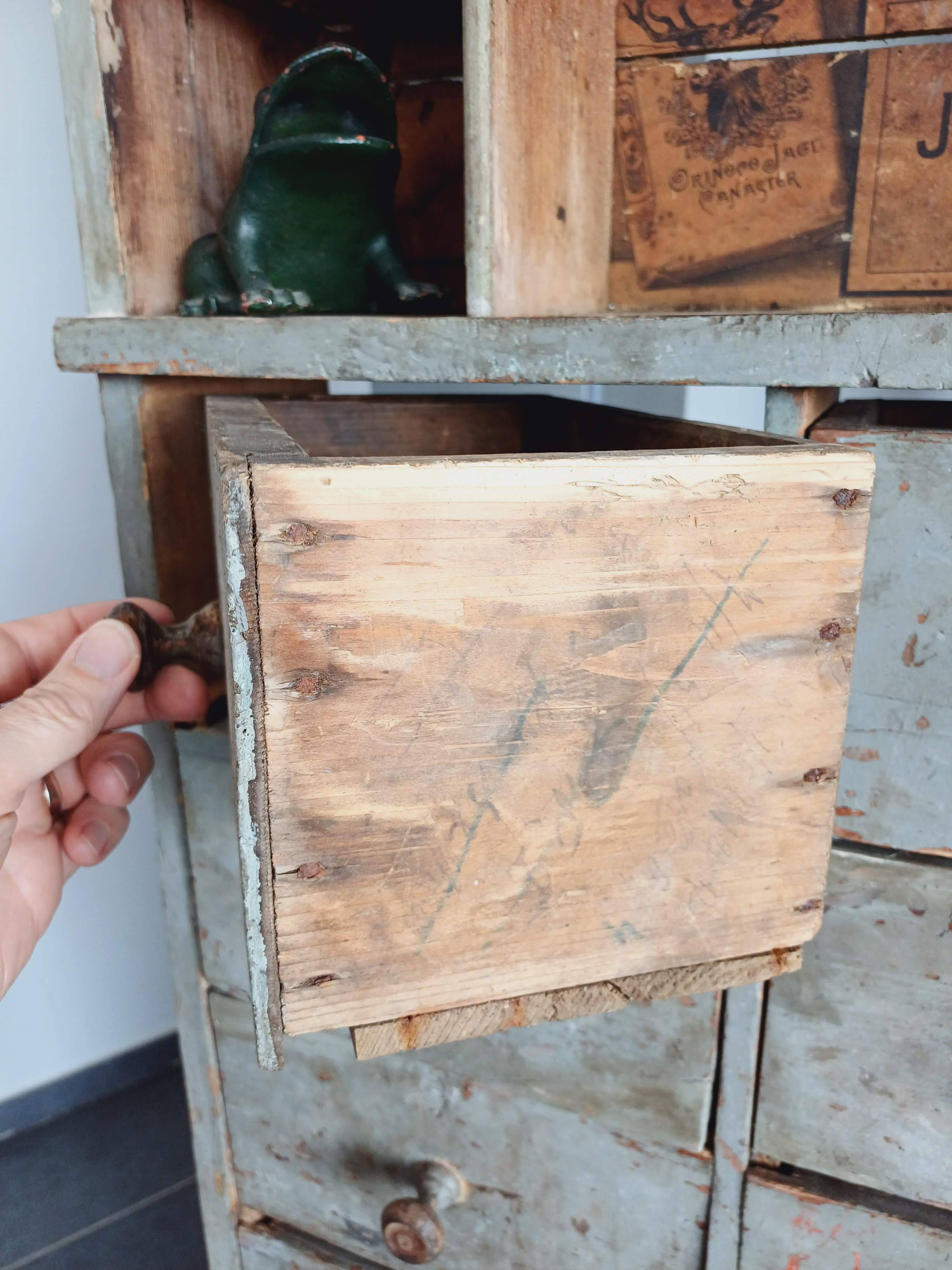 Craft cabinet with drawers with a very old tobacco advertisement in the background