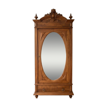 Antique solid wood wardrobe with an oval mirror.