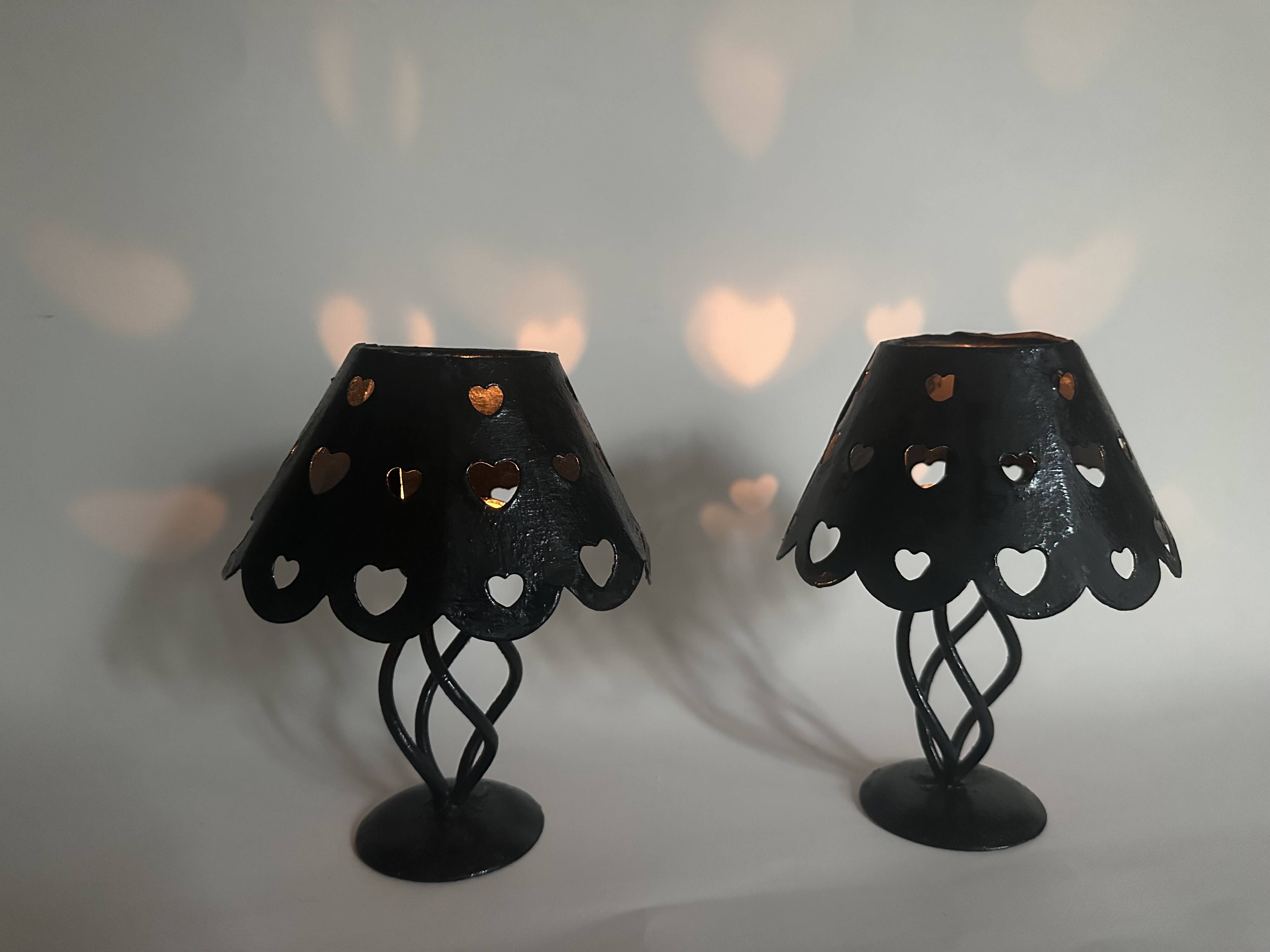 Pair of black wrought iron lanterns with heart patterns, romantic style.