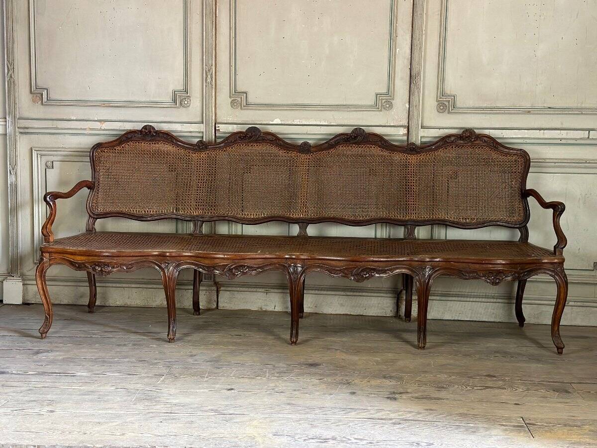 Grande banquette Louis XV en bois naturel mouluré et sculpté, France XVIIIème siècle