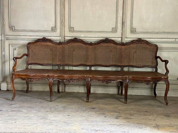 Grande banquette Louis XV en bois naturel mouluré et sculpté, France XVIIIème siècle