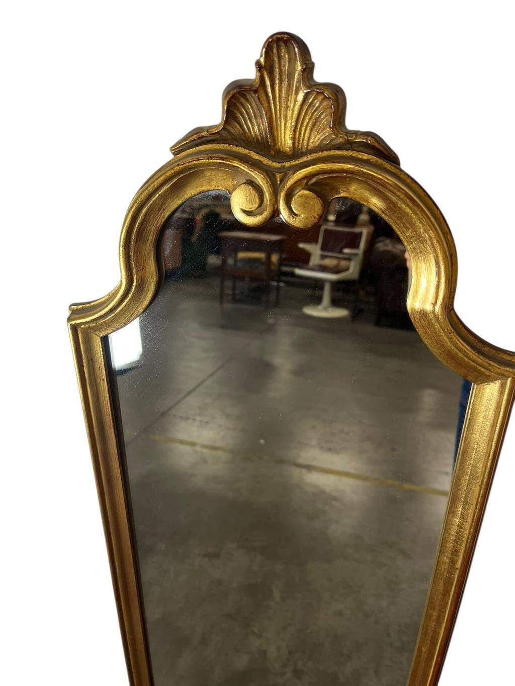 Narrow and tall antique mirror, adorned with golden patterns.