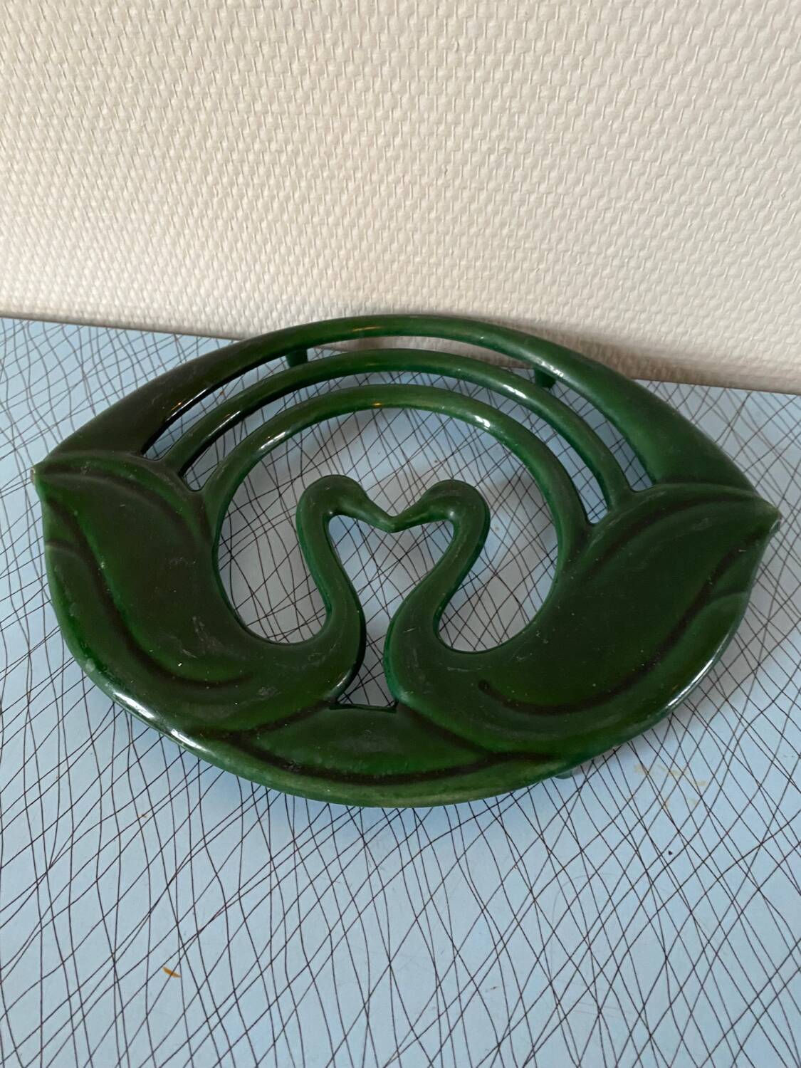 Enamelled cast iron trivet with sign decoration.