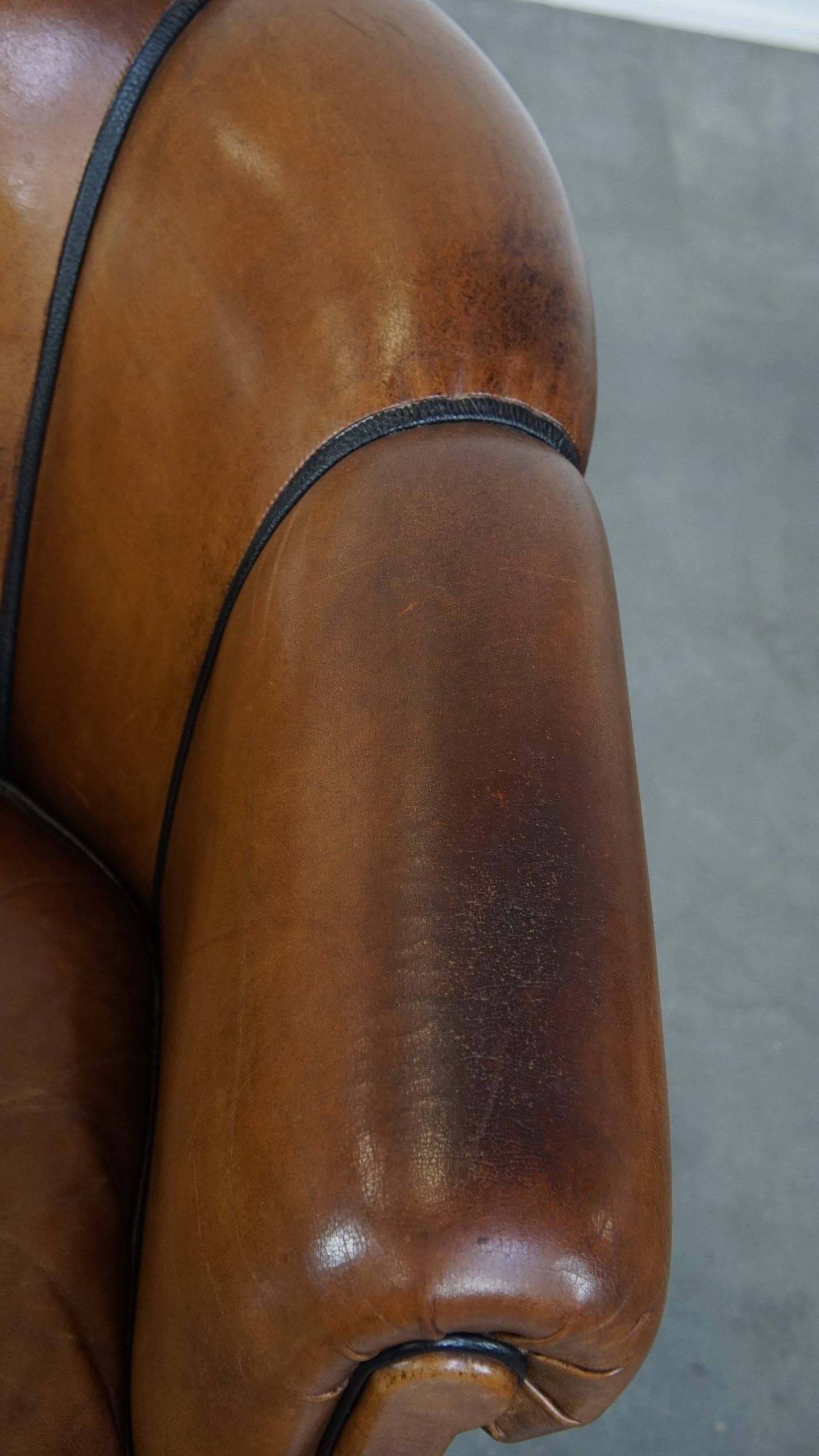 Unique vintage cognac-coloured leather club armchair with black piping