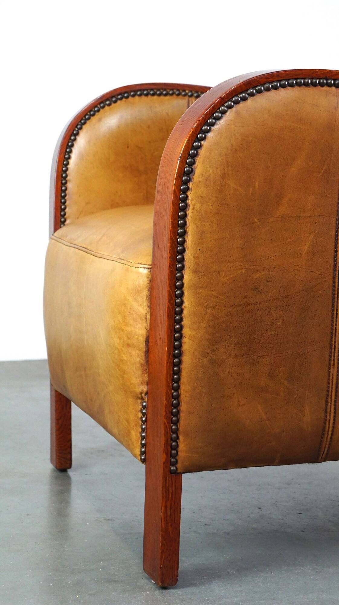 Luxurious cowhide Art Deco design armchair with wooden armrests and cognac-colored leather