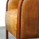 Luxurious cowhide Art Deco design armchair with wooden armrests and cognac-colored leather