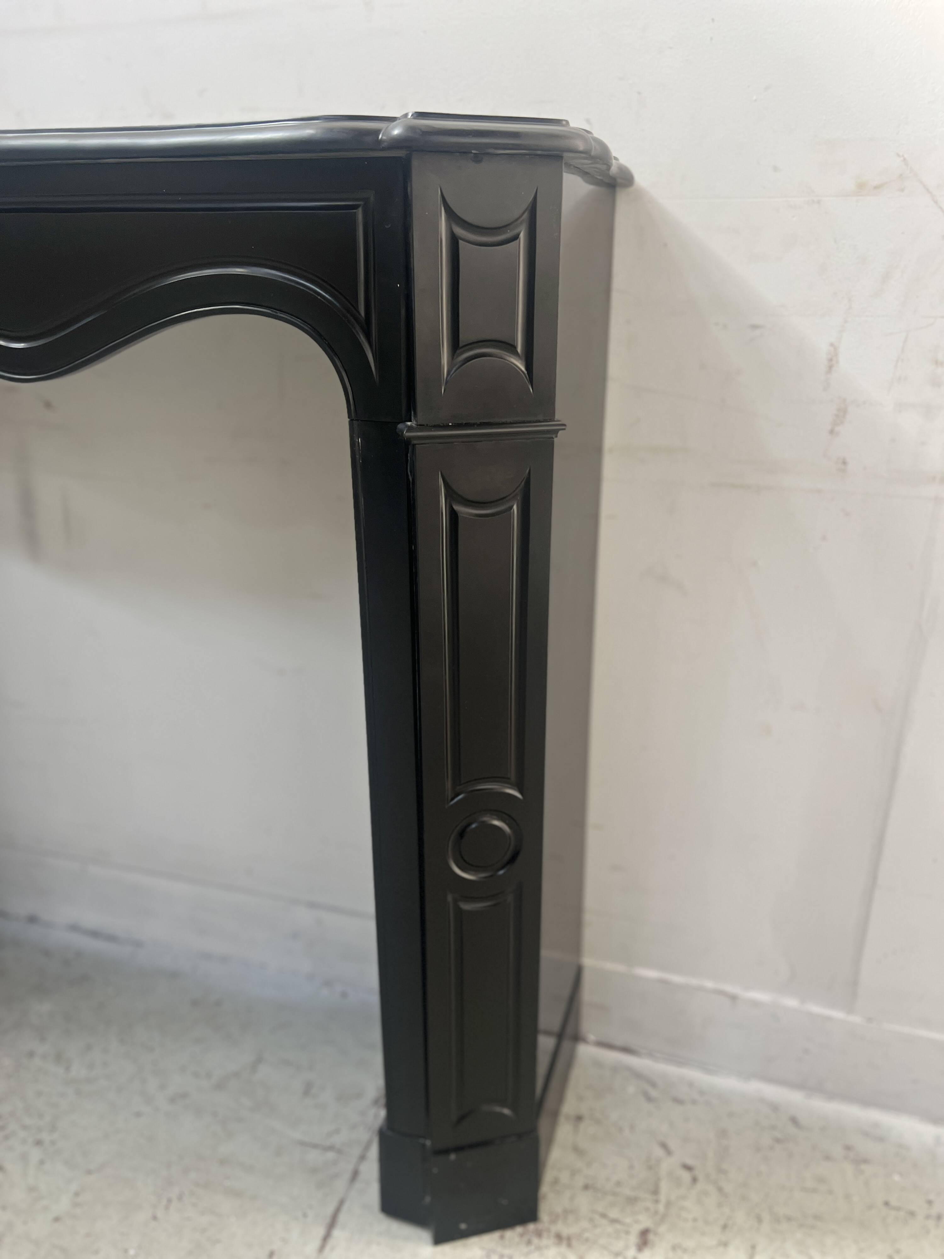 Cheminée de style Louis XV modèle Pompadour en marbre noir moucheté, XXe siècle