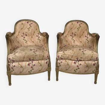 Paire de bergères en bois doré garnies de soie à motifs de fleurs, art déco d’inspiration Louis XVI