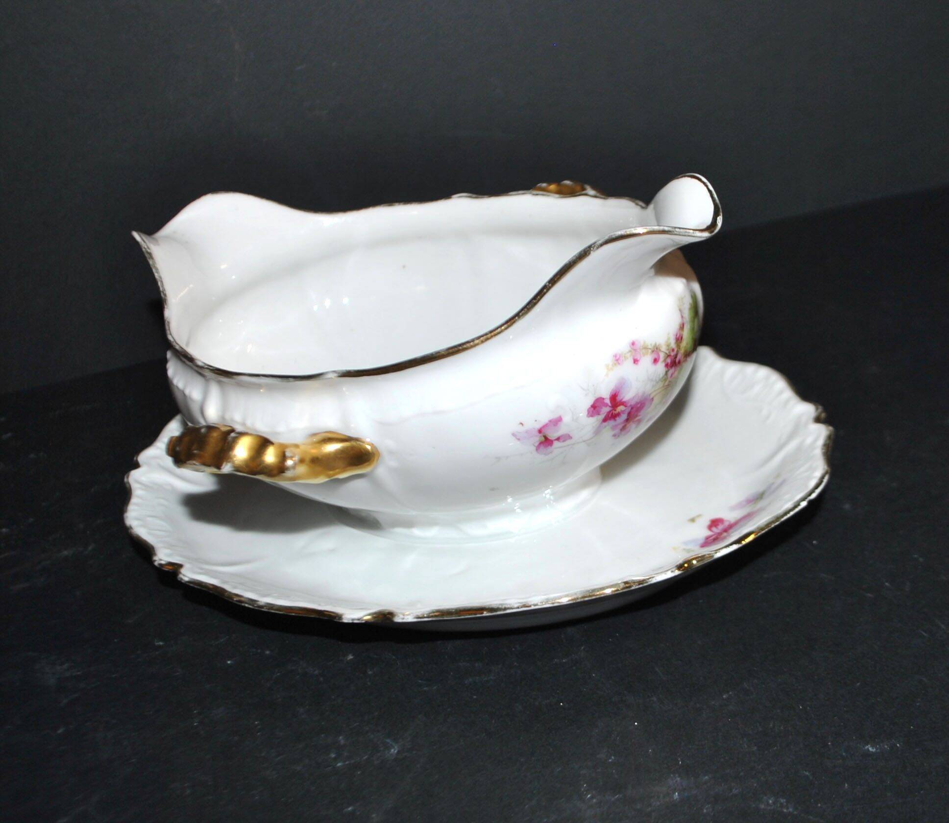Vintage pouring sauce boat in floral porcelain with gilding.