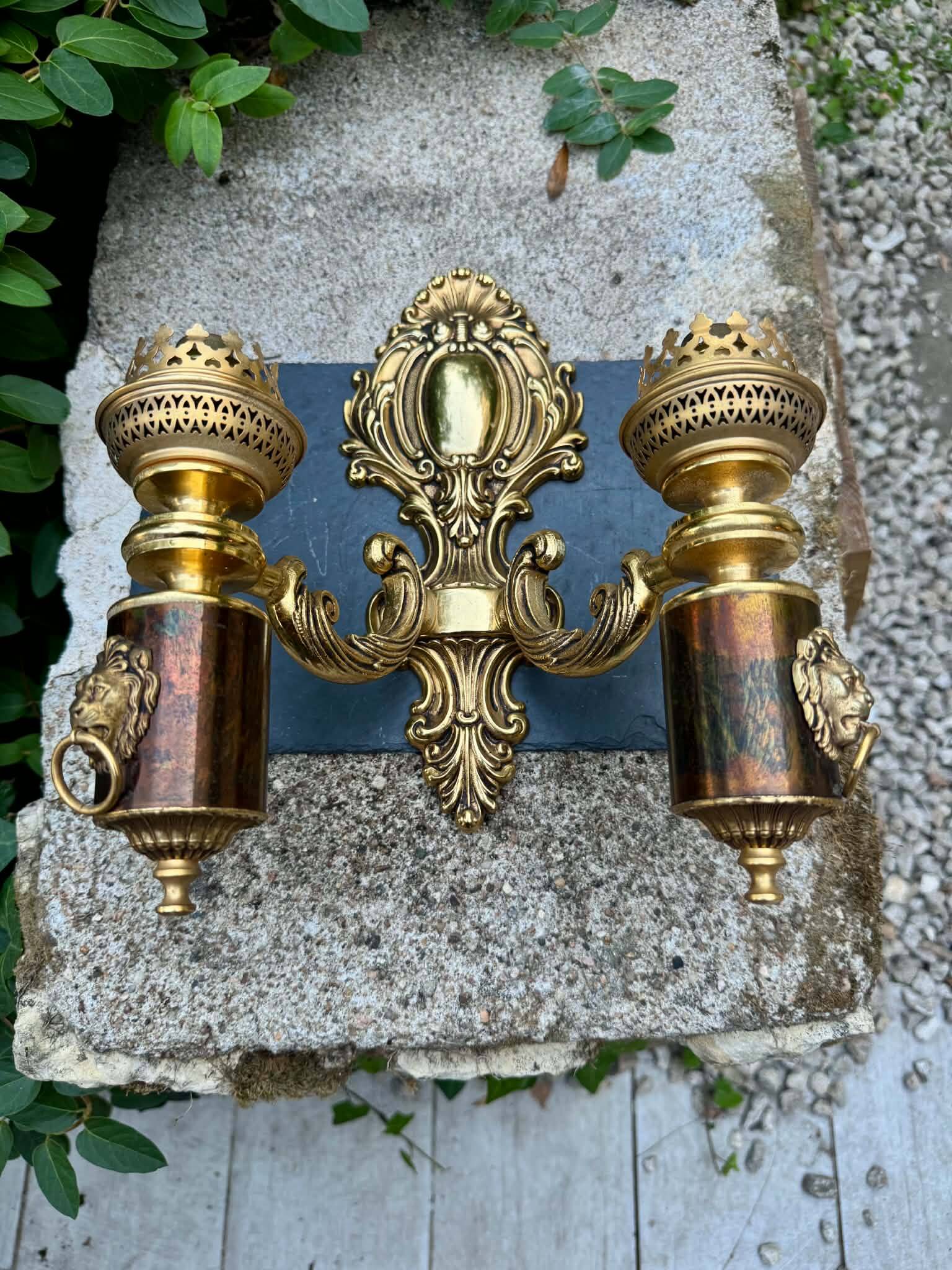 Wall light with 2 branches in baroque brass lion design.