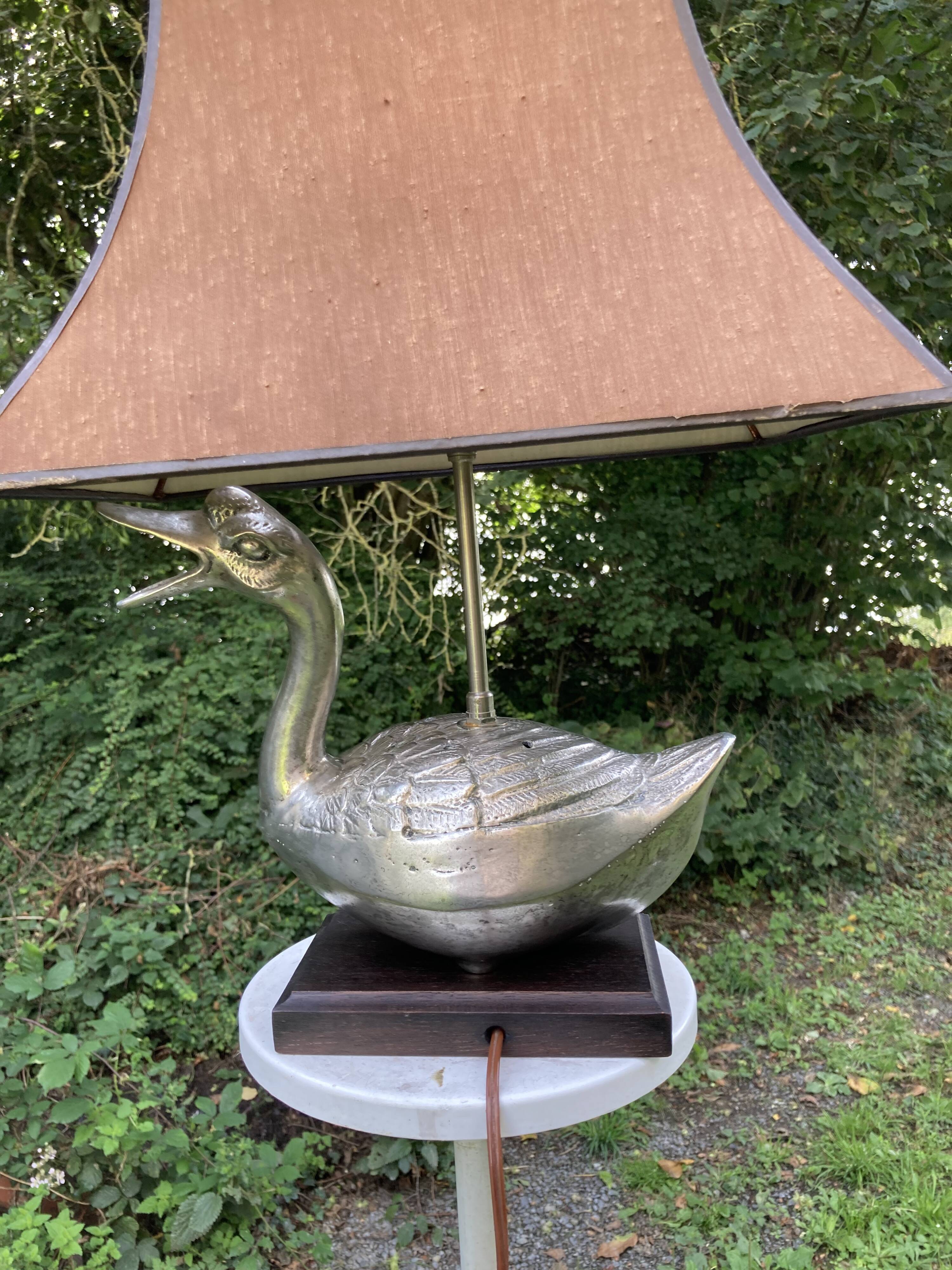 Old vintage lamp representing a duck in silver metal with wooden base