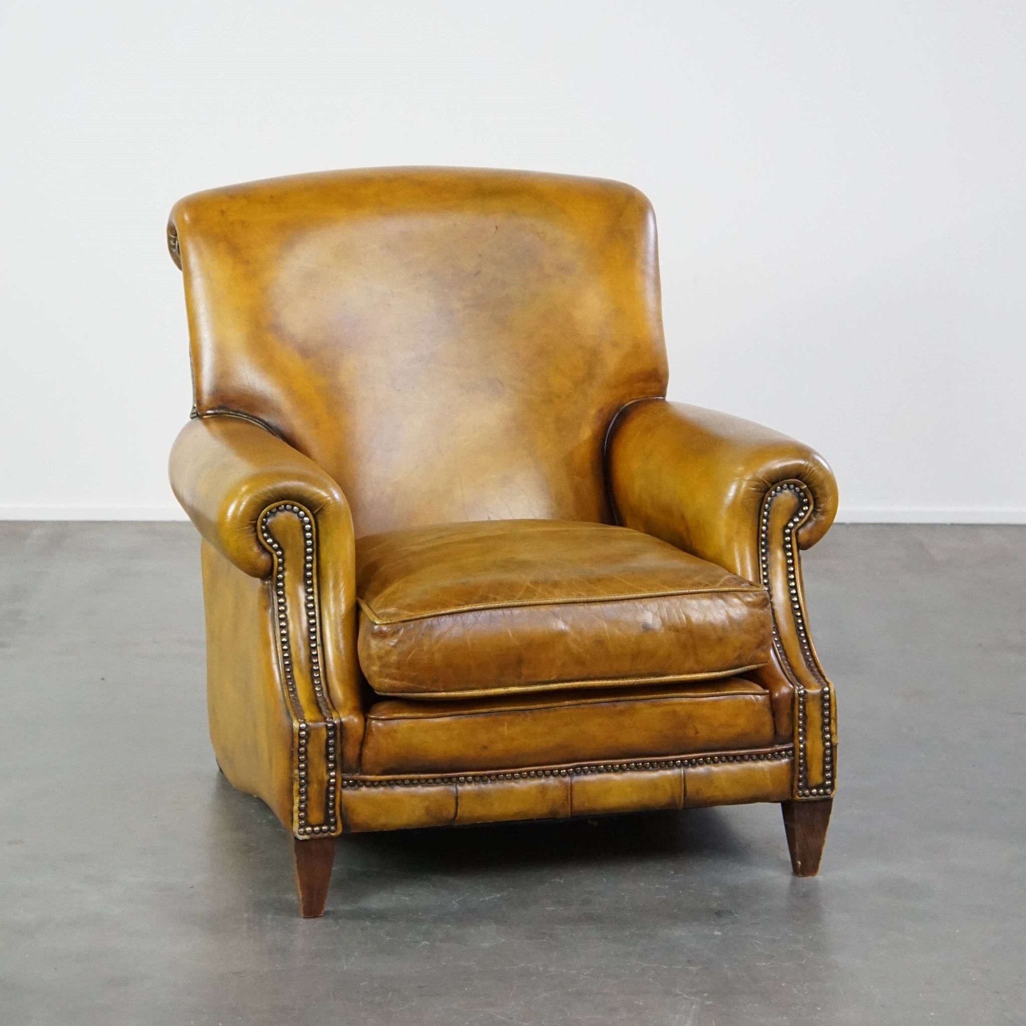 Comfortable large yellow English-style leather armchair with a fine finish and decorative nails