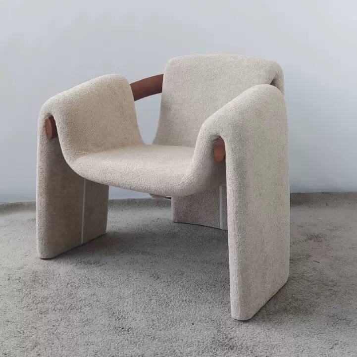 Sculptural lounge armchair in ecru boucle fabric with solid wood details.