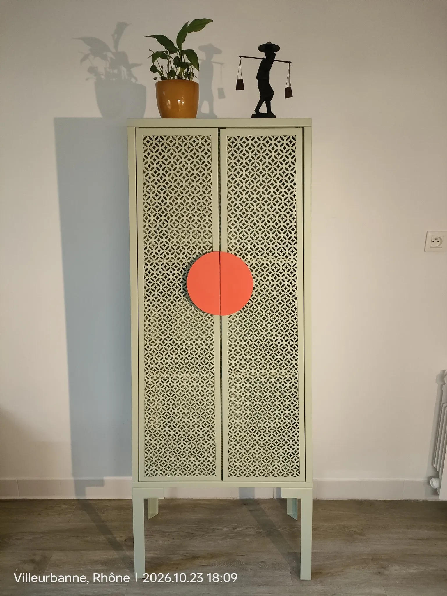 Vintage sage green metal wardrobe with louvered doors and coral handles.