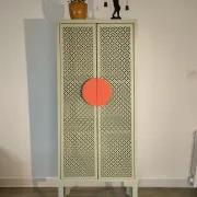 Vintage sage green metal wardrobe with louvered doors and coral handles.