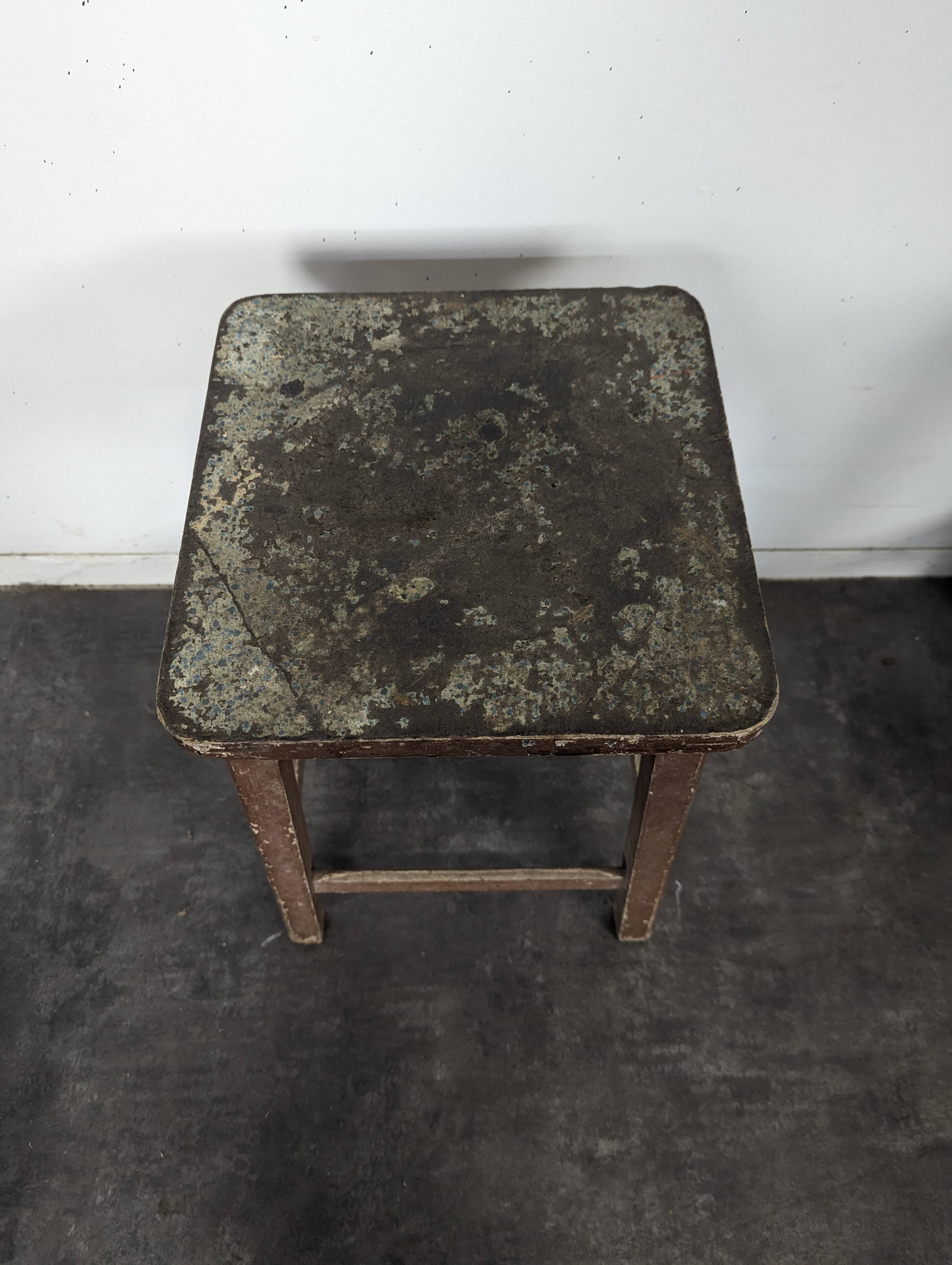 Brown painted wooden workshop stool with a patinated top.