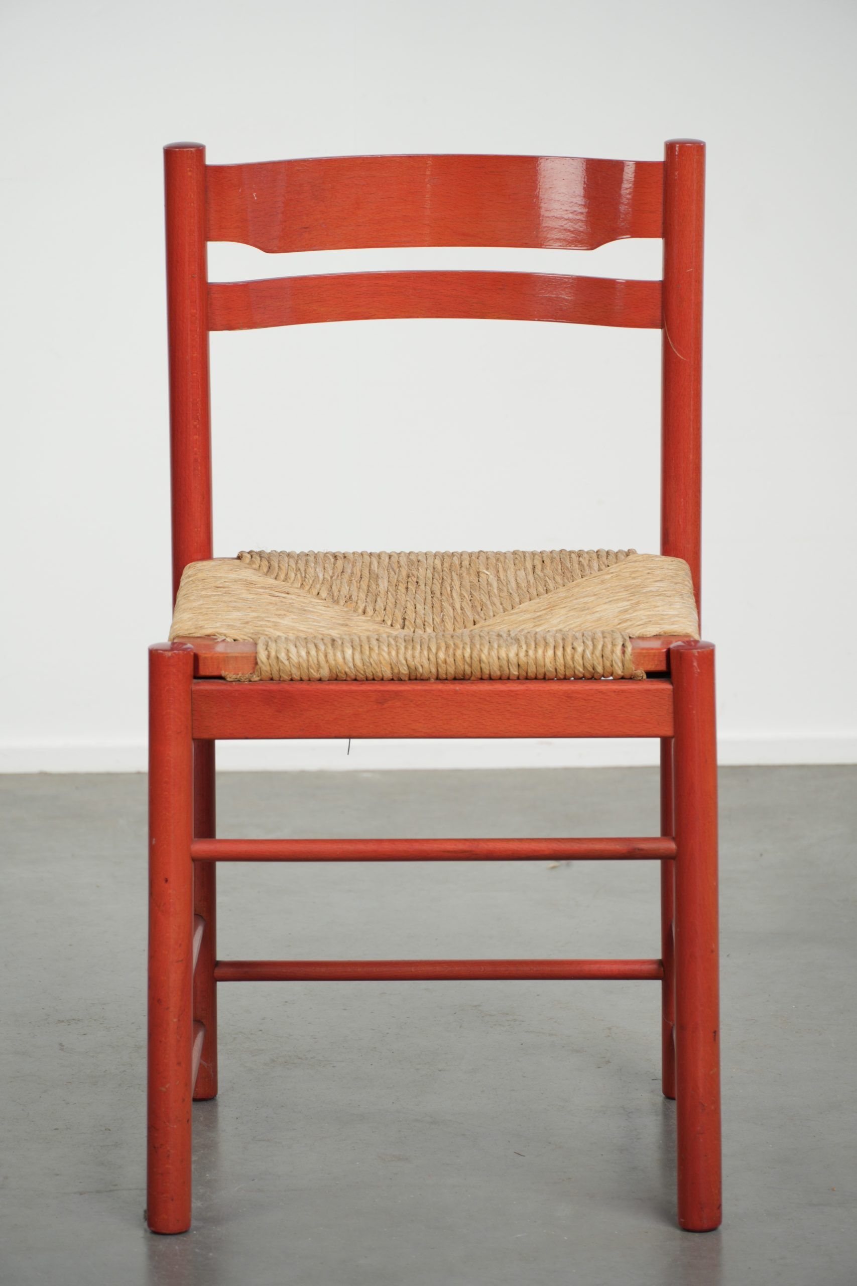 Red vintage wooden chair from the 1970s with a woven wicker seat