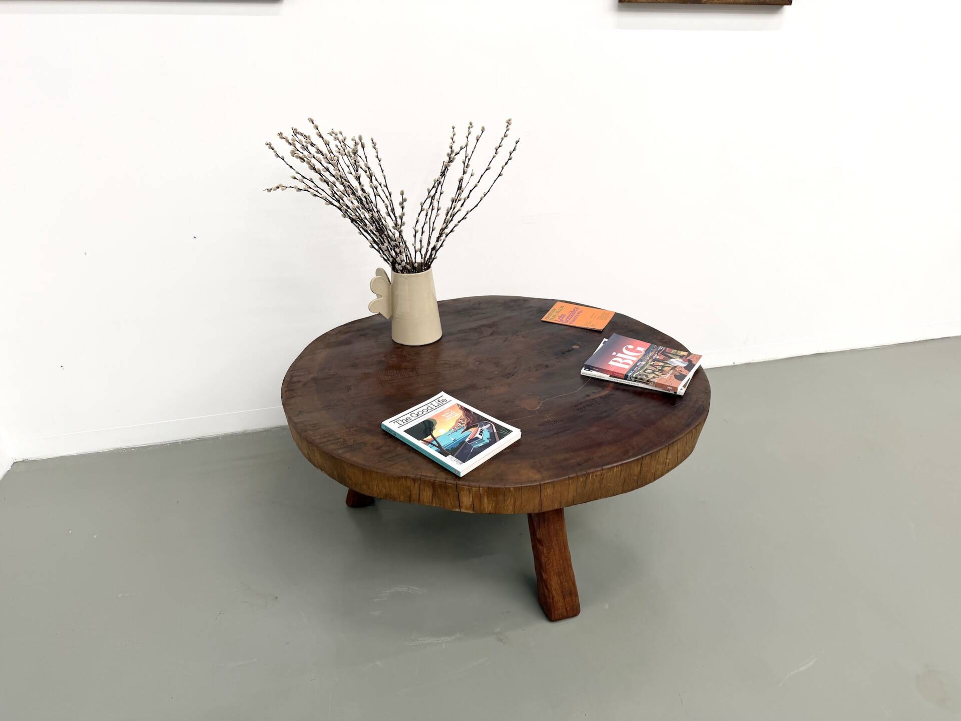 Brutalist coffee table in solid teak, monolithic slab, tripod base.