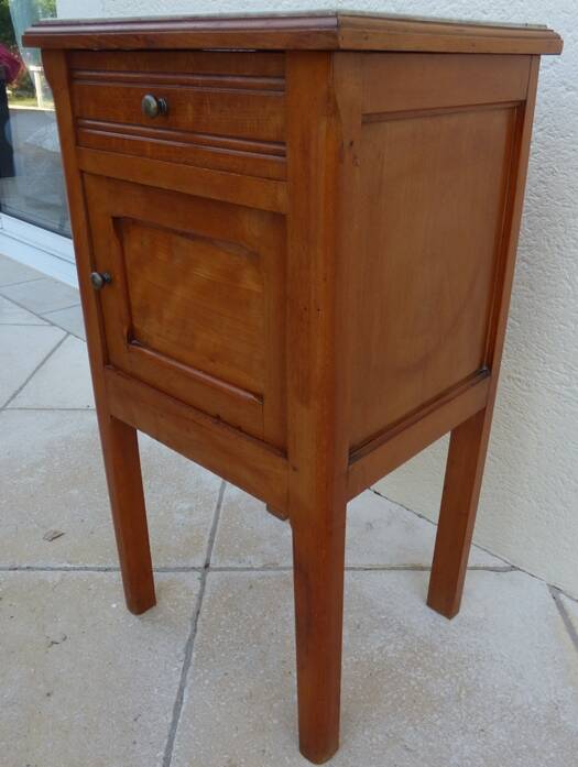 Antique bedside table with its marble top and white earthenware interior