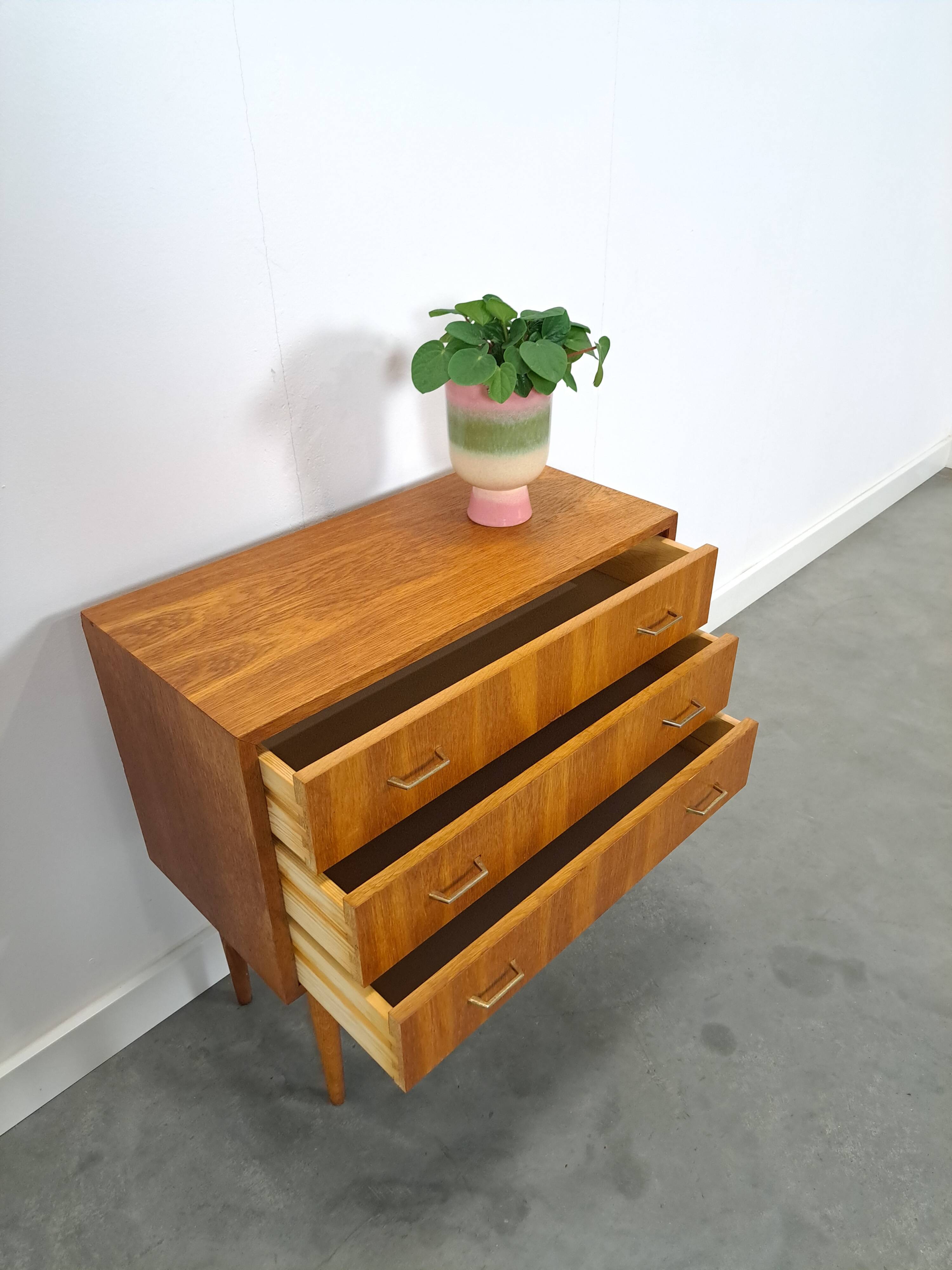 Commode danoise avec de hauts pieds et des poignées dorées.