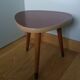 Tripod console table plant stand in the shape of a plectrum.