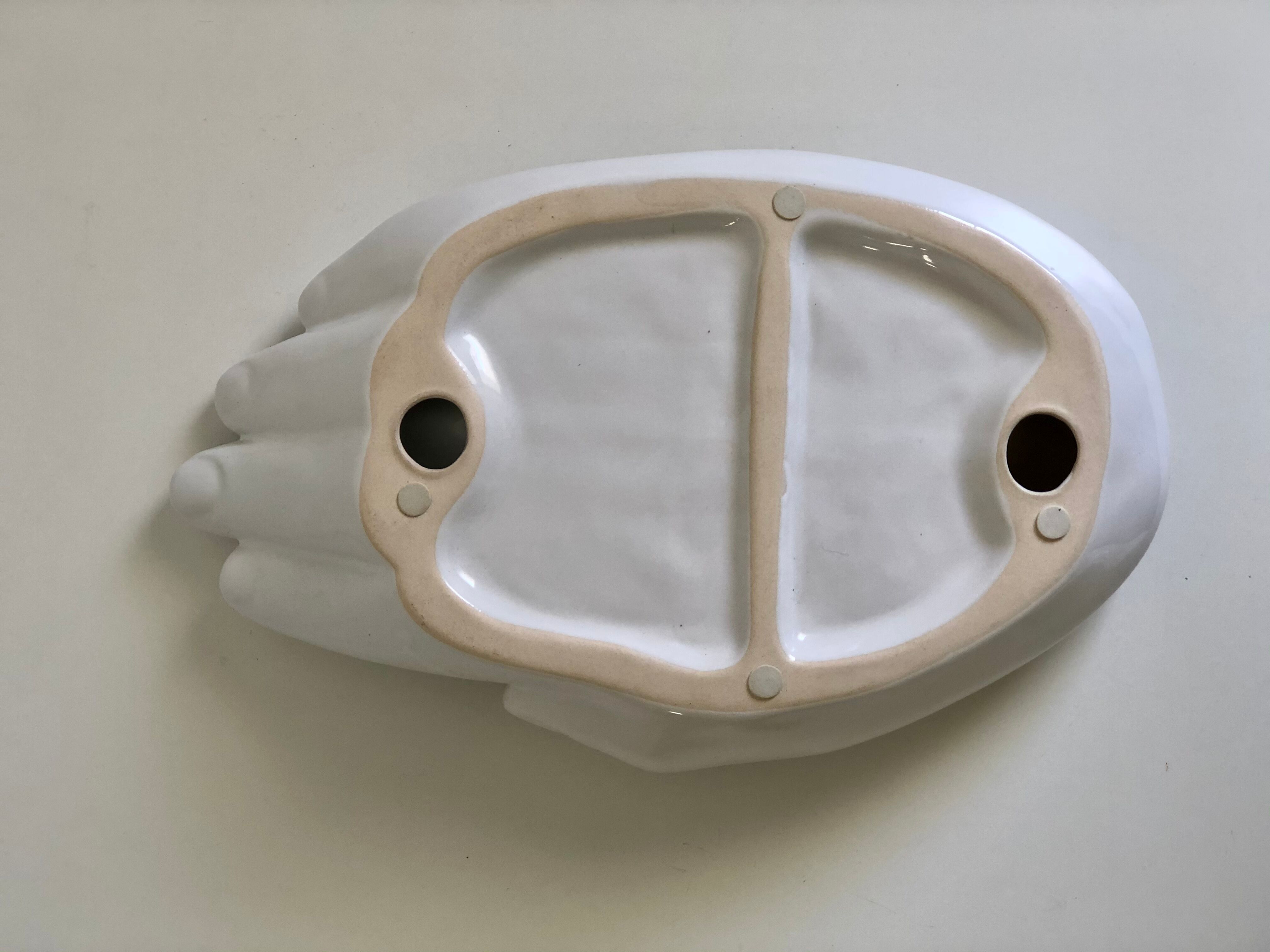 Empty white enamelled ceramic pocket in the shape of a large hand, 1990