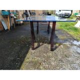 Vintage table with a glass top and smoked plastic trestle legs.