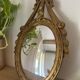 Oval convex witch mirror with golden ribbon mouldings.
