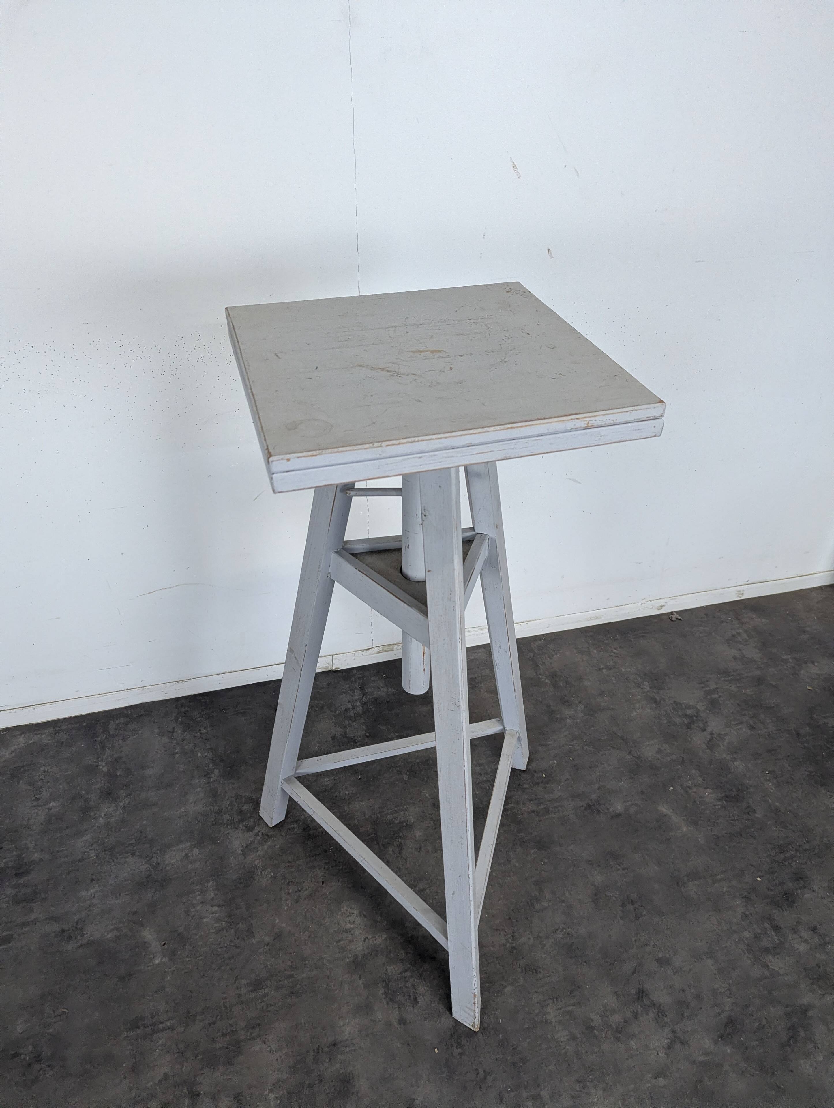 Tripod sculptor's stool in grey painted wood with a rotating top.