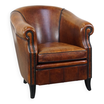 Sheepskin leather club armchair finished with decorative nails and black piping
