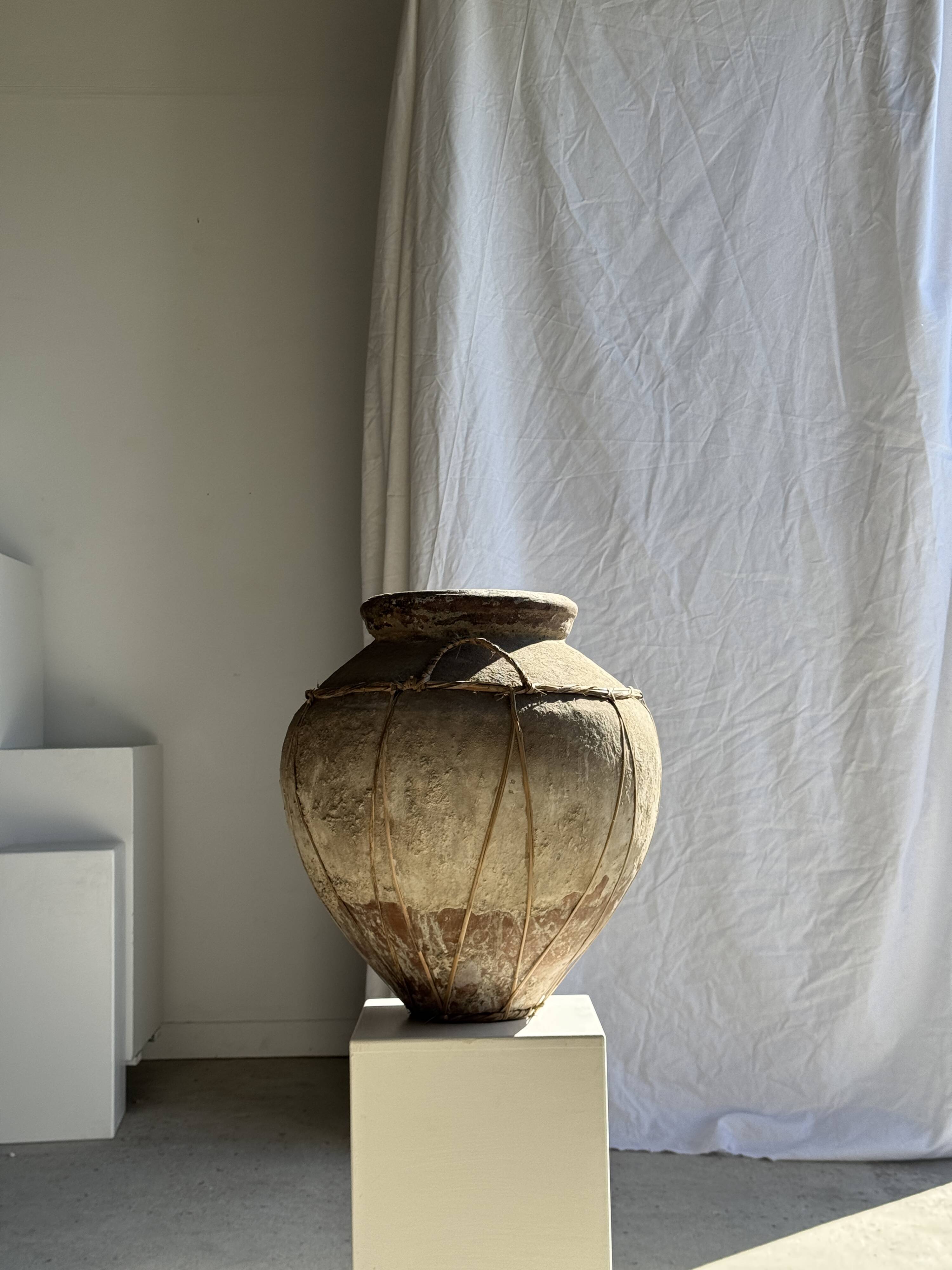 Very large grey and red terracotta pot with handles and rattan crossbars.