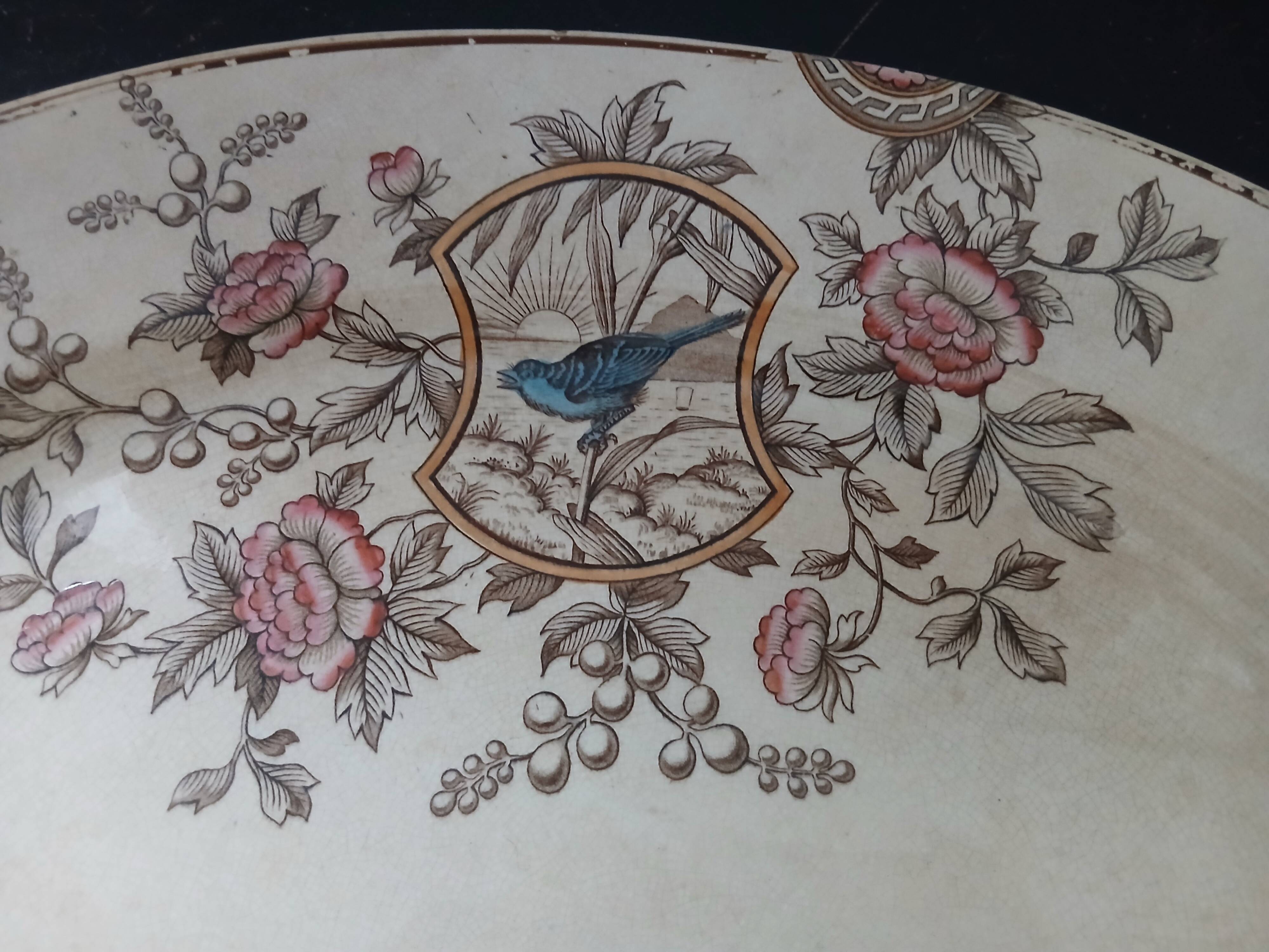 Large antique plate stamped with a fauna and flora pattern.