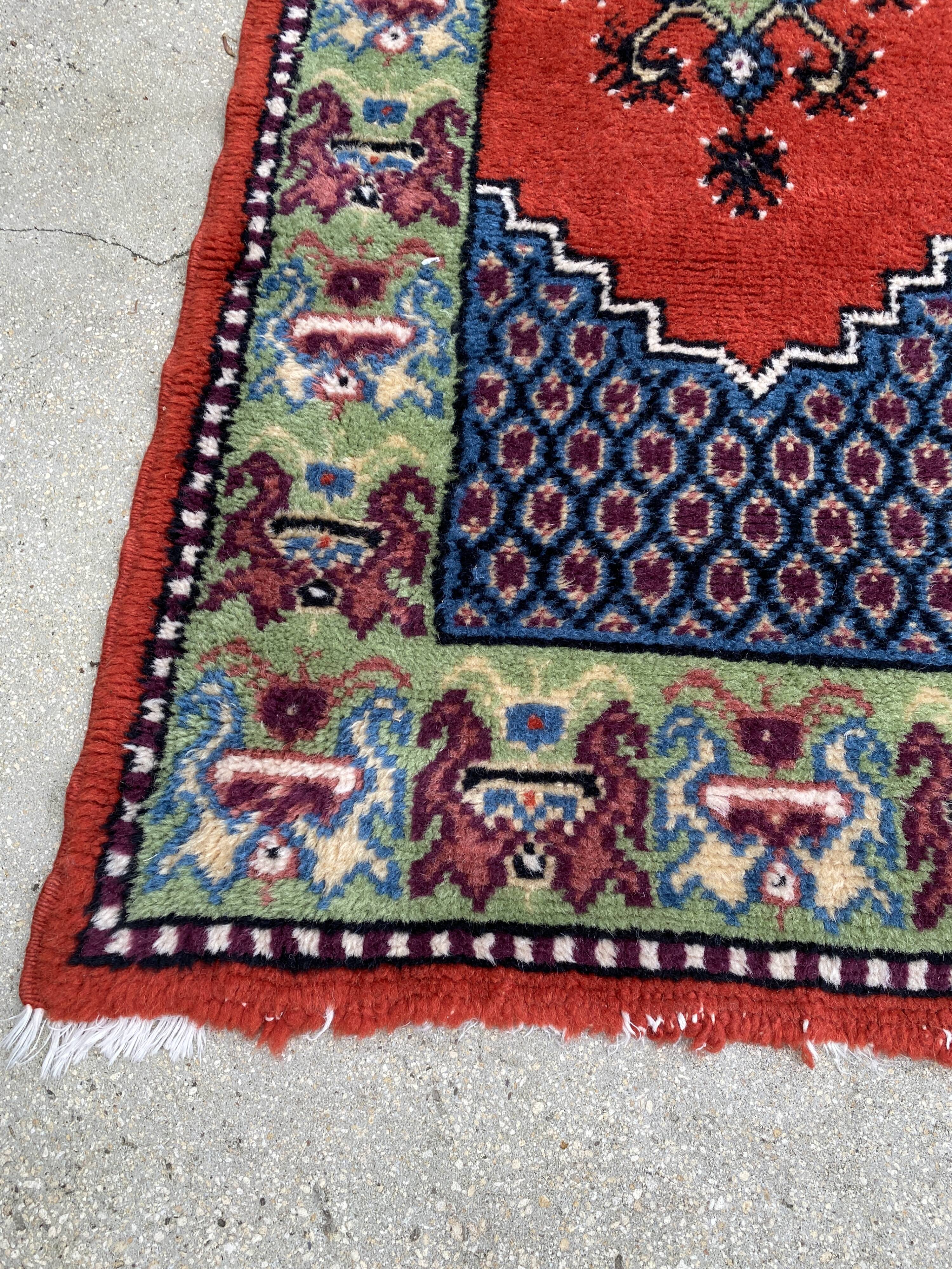 Vintage hand-knotted wool rug with polychrome decoration on a red, blue, green background 150 x 63 cm