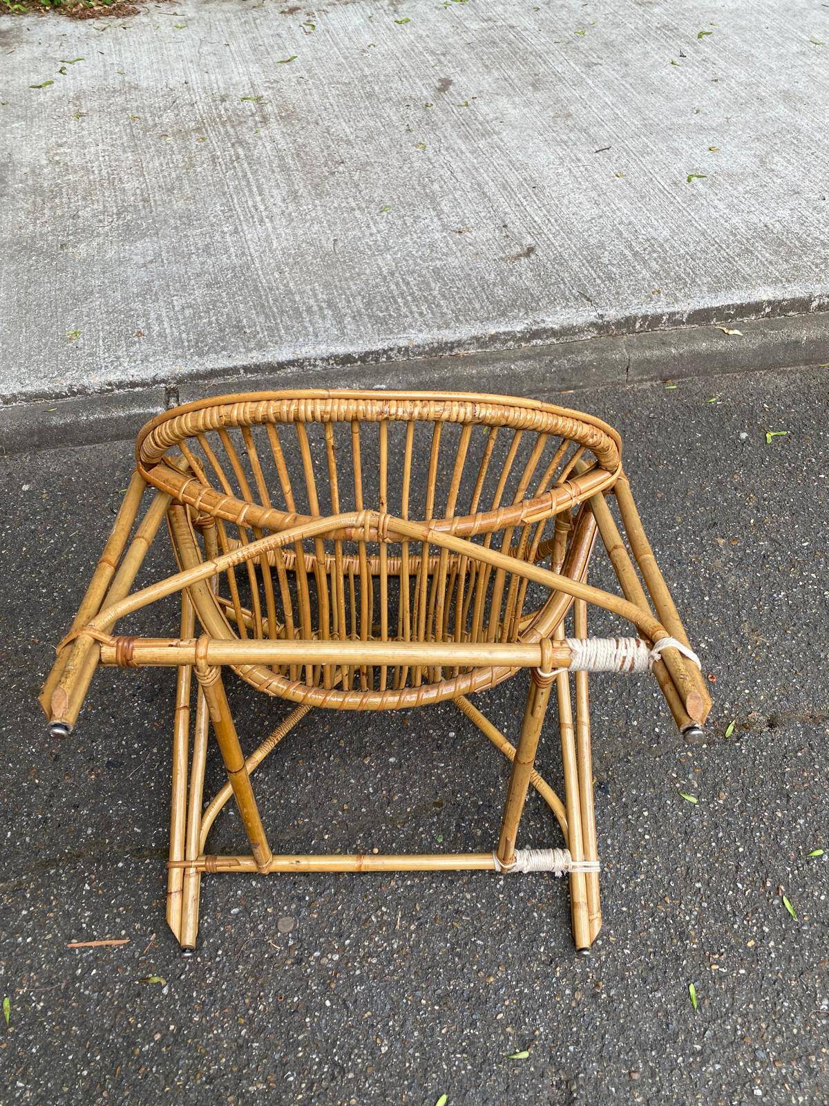 1970s adult rattan and wicker armchair with a round burgundy velvet cushion.