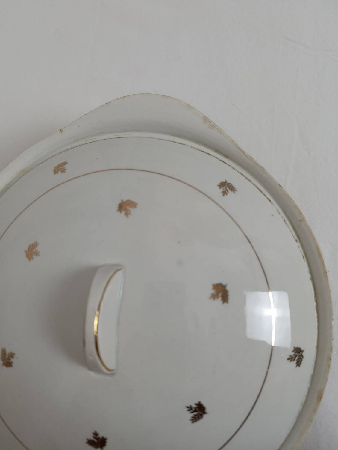 White earthenware soup tureen with a golden pattern.