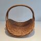 Woven Rattan Log Holder in a Semi-Round Shape with a Central Arched Handle.