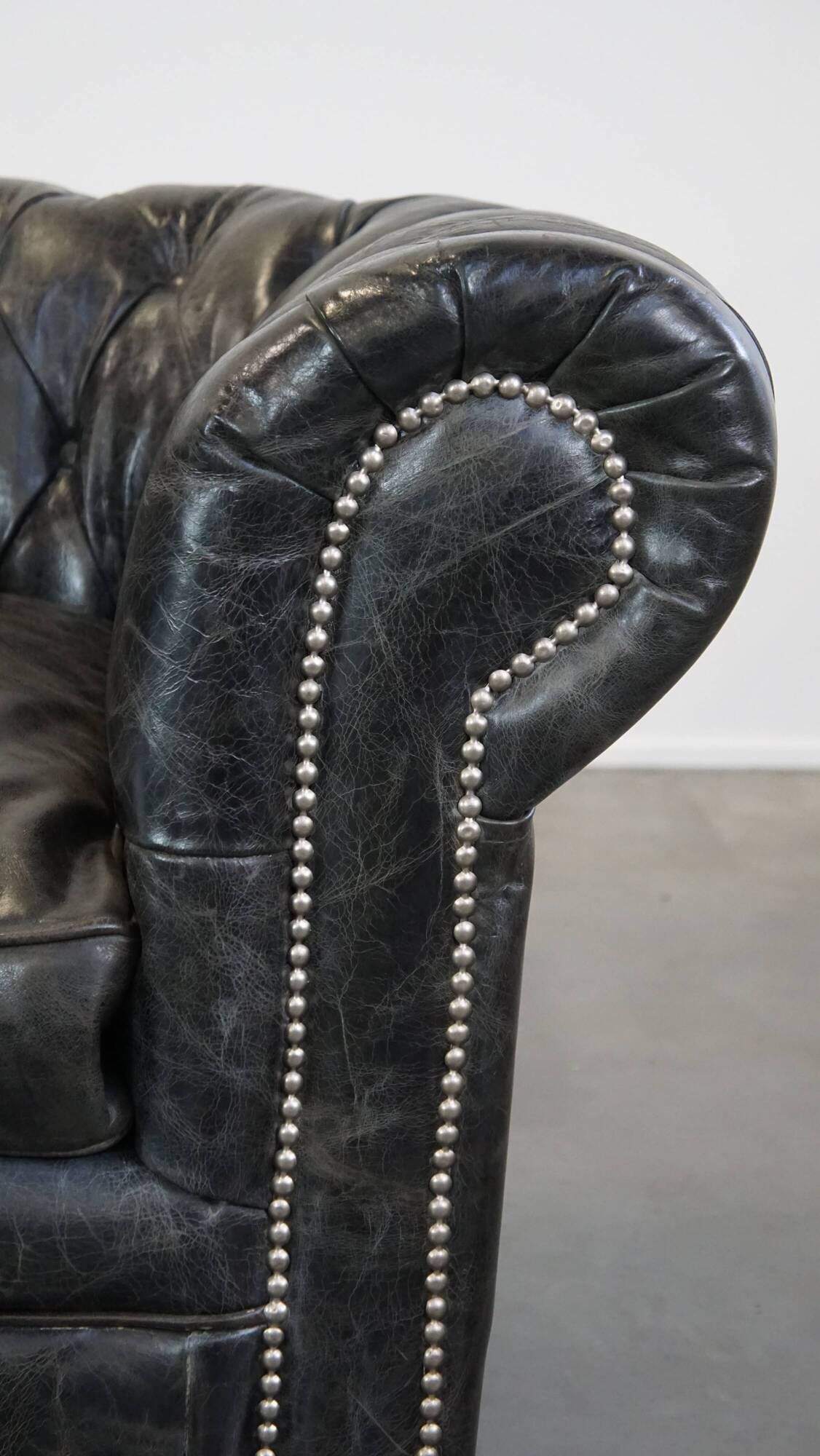 Spacious black cow leather chesterfield armchair with distinctive character