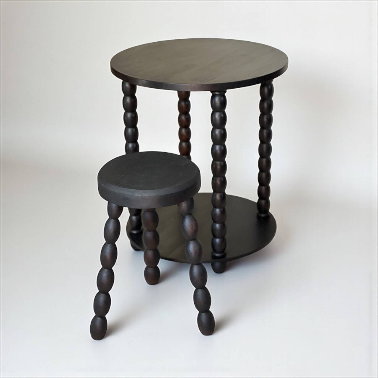 Set of side table and 2 stools, stained black wood, Circa 1950.