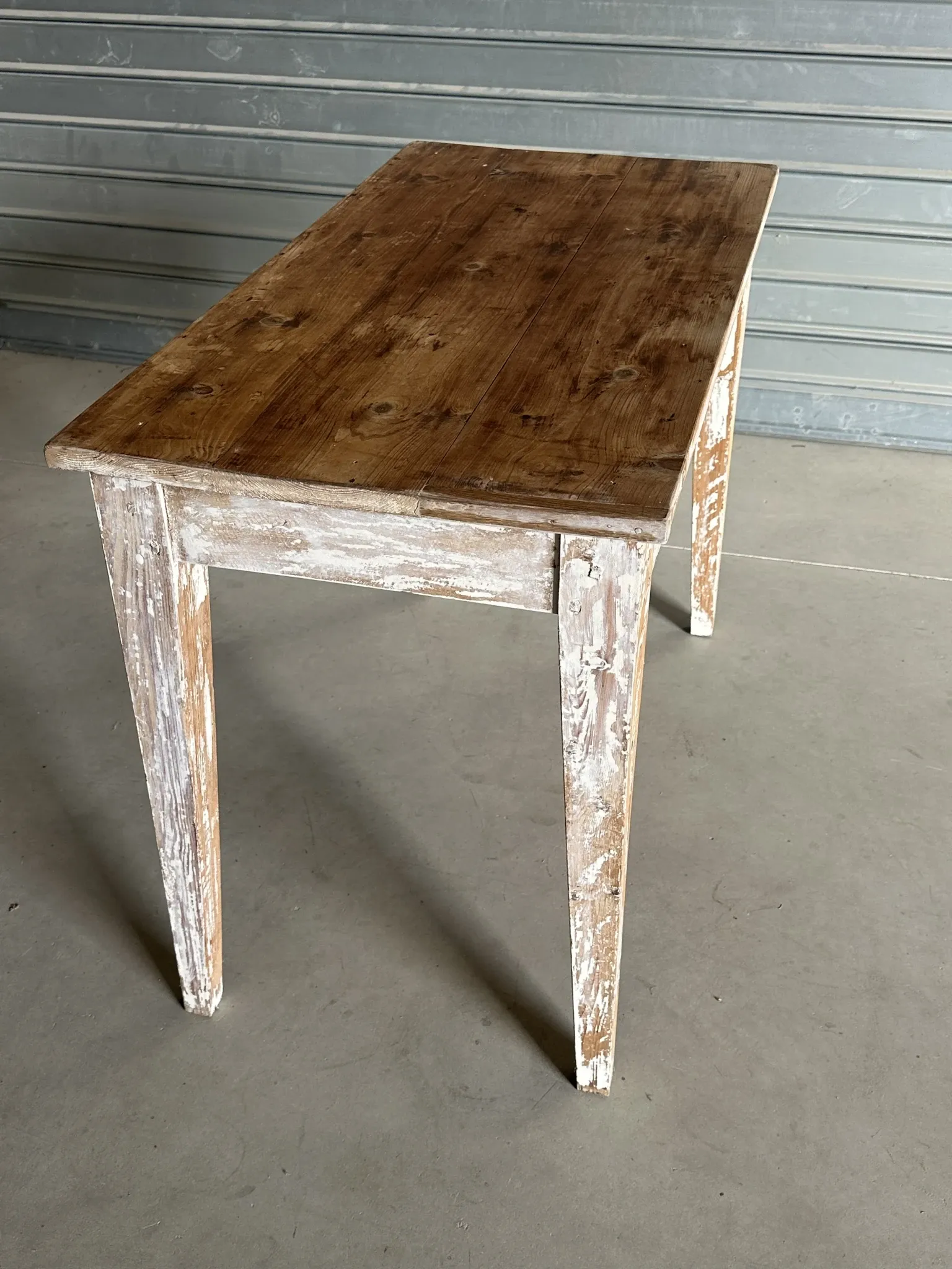 Vintage table made of raw wood with a distressed white base.