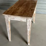 Vintage table made of raw wood with a distressed white base.