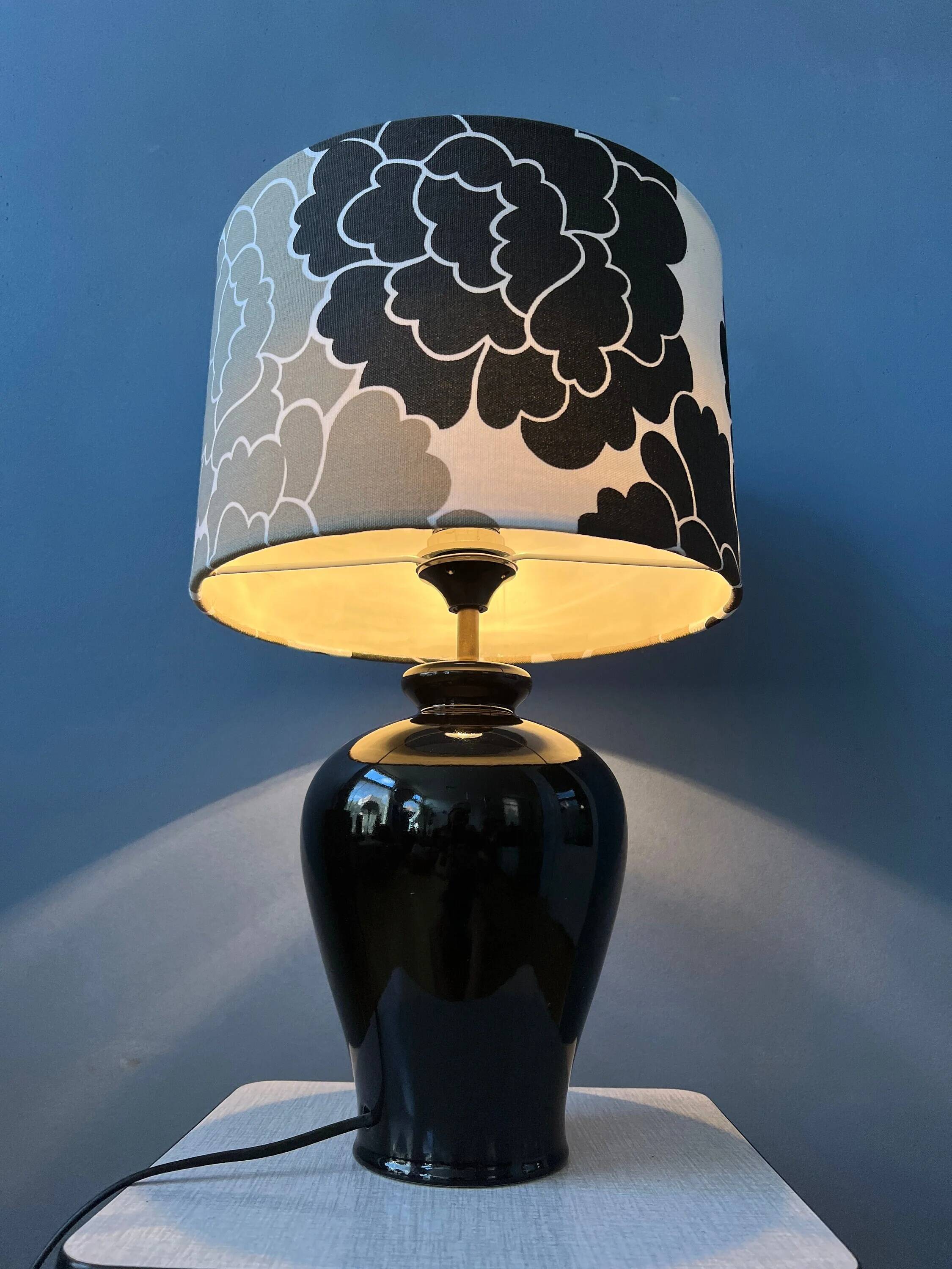 Small Space Age table lamp with a porcelain base and black and white flower shade.