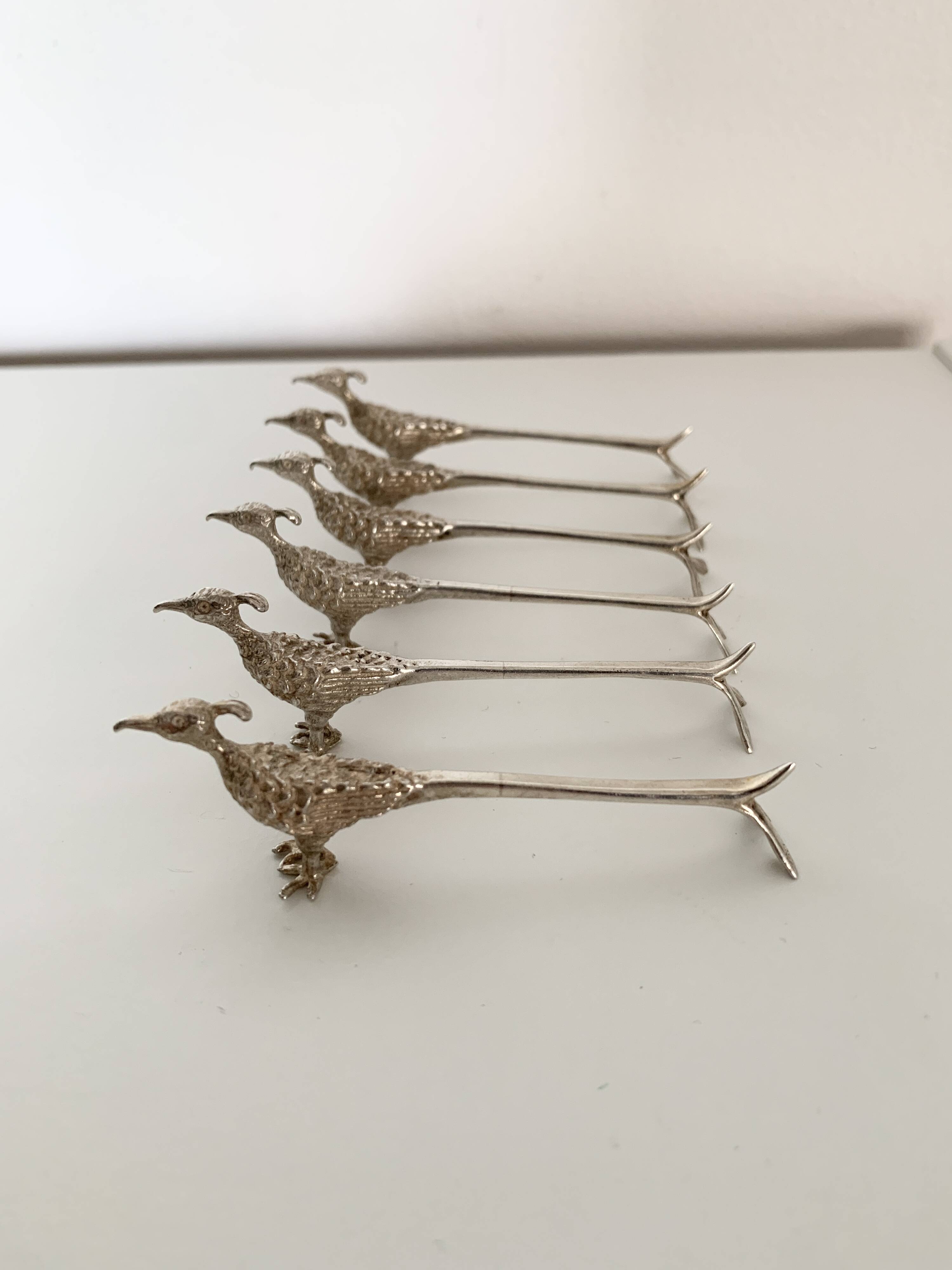 Six silver-plated knife rests in the shape of peacocks.