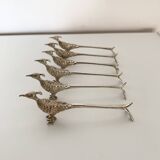 Six silver-plated knife rests in the shape of peacocks.