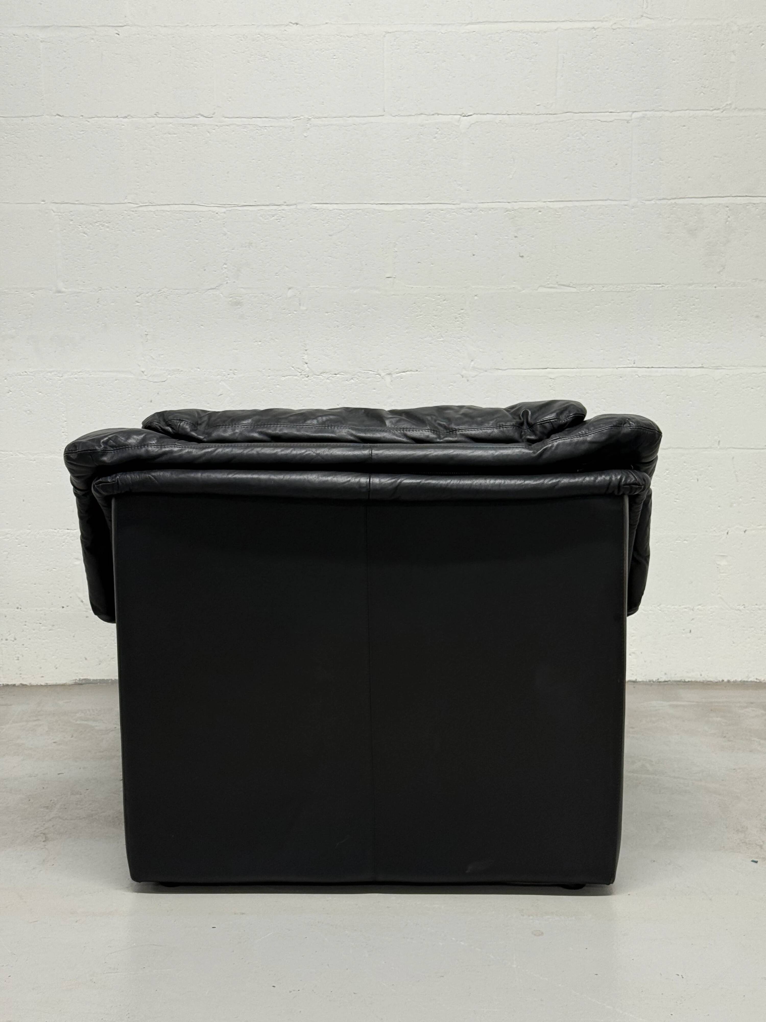 Vintage black leather lounge chair — low postmodern club chair from the space age.