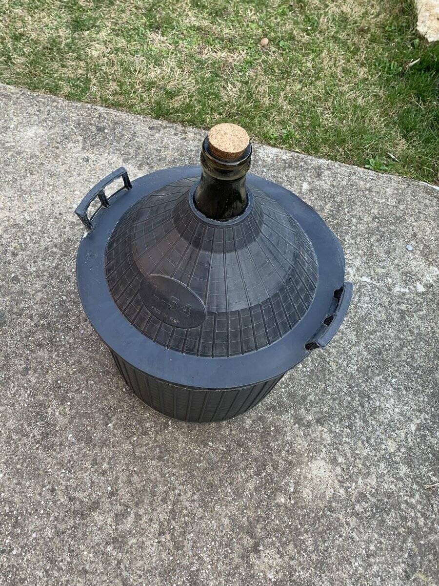 Dame-Jeanne vintage in olive green glass with a basket and black plastic lid.